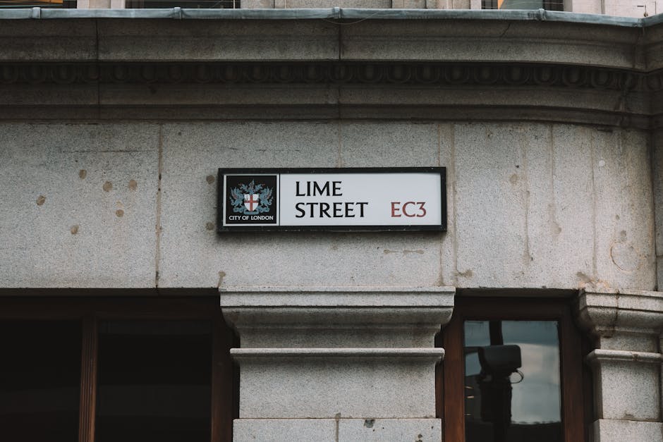 A close-up view of a street sign mounted on a stone building façade indicating 'LIME STREET' in bold black lettering, with the postal code 'EC3' in red on the right. The sign includes the City of Lon